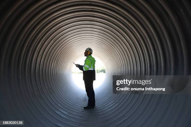 civil engineer with green reflective safety jacket working in a huge tube at construction site line - civilperson stock pictures, royalty-free photos & images