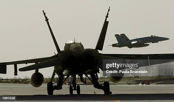 Air Force F-18 takes off as another waits for clearance on the tarmac March 28,2003 at an air base in Kuwait, as Operation Iraqi Freedom continues...