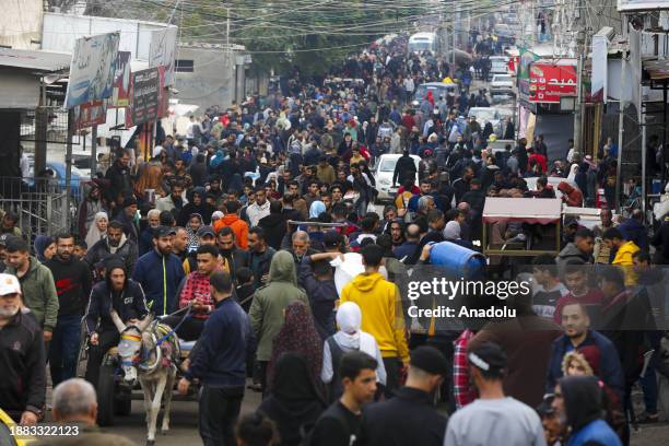 Displaced Palestinians, moved to Gaza's Deir al Balah seeking refuge from Israeli attacks, are seen amid destruction on December 27, 2023....