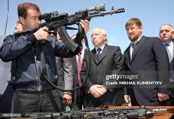 Russian President Dmitry Medvedev holds a submachine gun as Dagestan President Mukhu Aliev and Chechen President Ramzan Kadyrov watch during his...