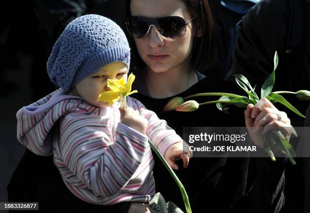 Little holds flowers as people wait for the funeral cortege of late Polish President Lech Kaczynski and his wife Maria in Krakow on April 18, 2010....