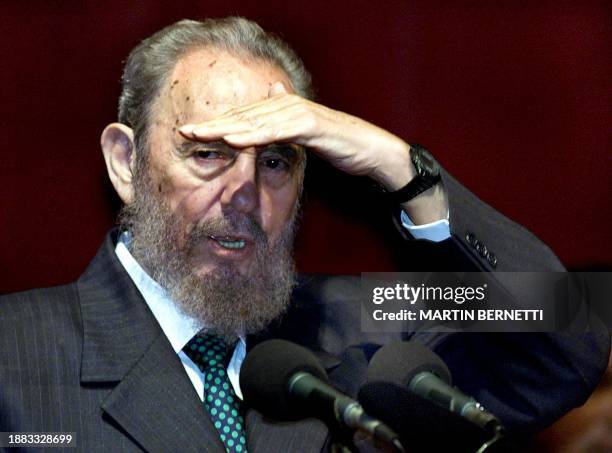 Cuban President Fidel Castro shields his eyes from stage lights during a speech at the Culture House in Quito, 30 November, 2002. Castro is in...