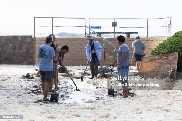 Ventura, CA Pierpont neighbors help shovel sand on Bath Lane to help water drain after a seawall and sand berm was breached by high surf on Thursday,...