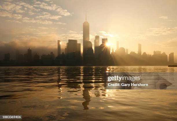 The sun rises behind the skyline of lower Manhattan and One World Trade Center in New York City on December 25 as seen from Jersey City, New Jersey.