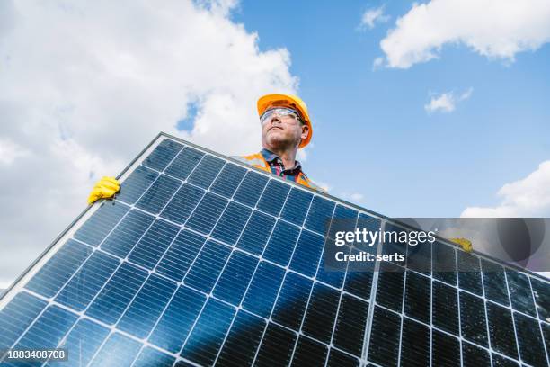 solar panel pioneer: male engineer holding panel in photovoltaic farm power station - zonnepanelen stockfoto's en -beelden