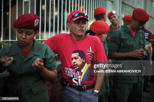 Supporter of Venezuelan President Hugo Chavez waits in line to vote next to National Guard soldiers at a polling station in Caracas on September 26,...