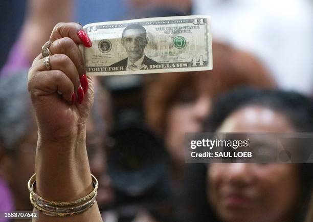 Woman holds up a US dollar bill with a picture of US President Barack Obama as he attends a town hall event on the economy at Racine Memorial Hall in...