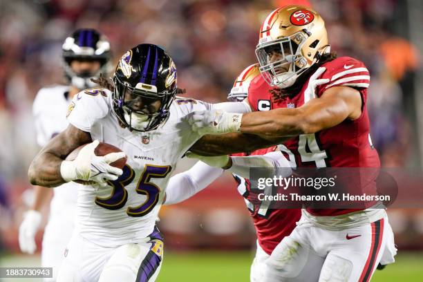 Gus Edwards of the Baltimore Ravens stiff arms Fred Warner of the San Francisco 49ers during the third quarter at Levi's Stadium on December 25, 2023...
