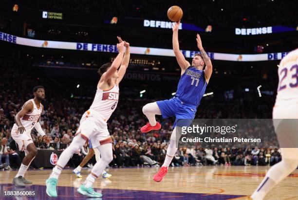 Luka Doncic of the Dallas Mavericks attempts a shot over Grayson Allen of the Phoenix Suns during the first half of the NBA game at Footprint Center...