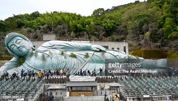 People clean up the Reclining Buddha with bamboos at Nanzoin Temple on December 26, 2023 in Sasaguri, Fukuoka, Japan. Some 200 monks and parishioners...
