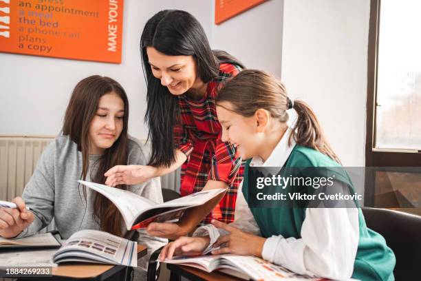 insegnante che aiuta le sue studentesse alla scuola elementare di lingue - lingua inglese foto e immagini stock