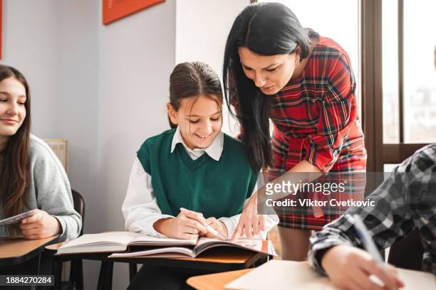 female teacher helping her student at elementary language school - education occupation stock pictures, royalty-free photos & images