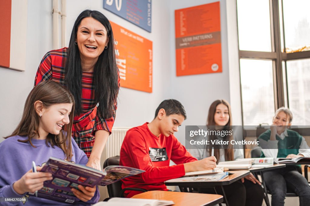 Female teacher helping her students in a classroom at elementary language school