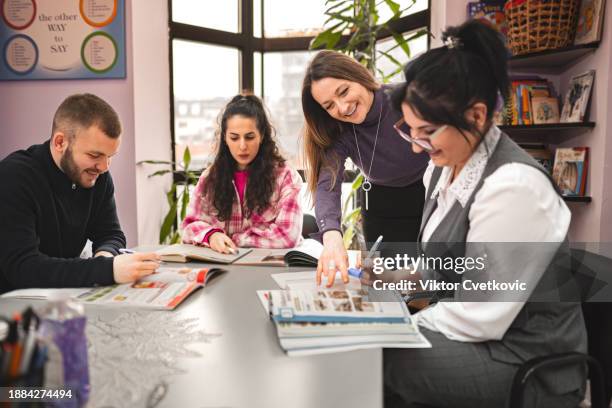 female teacher helping her millenial students in language school - lingua inglese foto e immagini stock