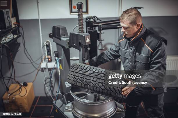 mechaniker beim aufsetzen des reifens auf die felge - felge stock-fotos und bilder