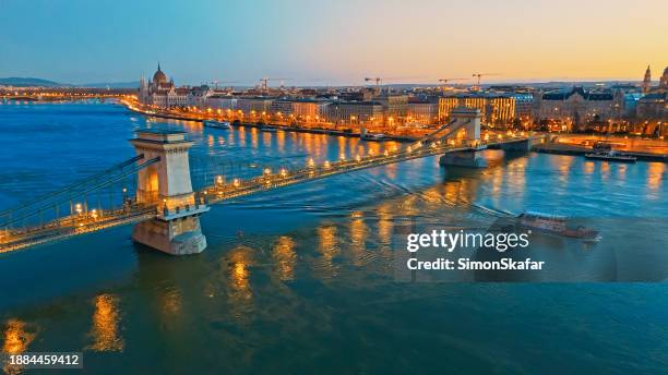 illuminated szechenyi chain bridge over danube river with budapest parliament building in background at night,hungary - chain bridge suspension bridge stock pictures, royalty-free photos & images