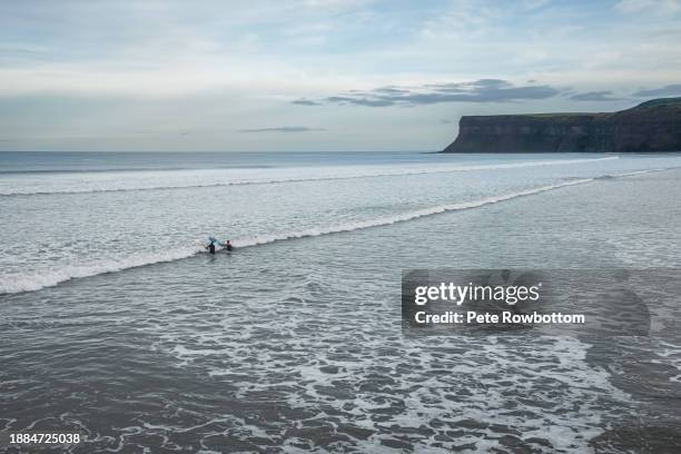 surfers head out to sea - saltburn stock pictures, royalty-free photos & images