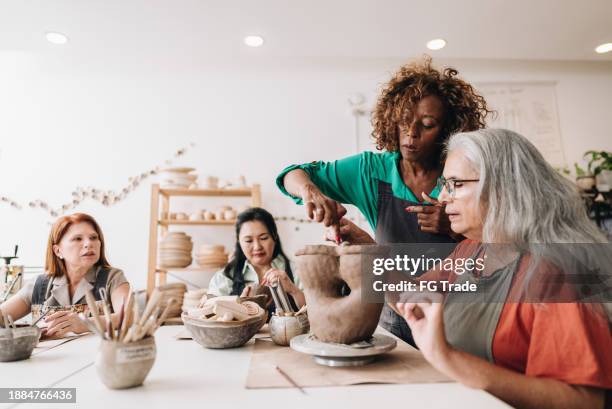 pottery teacher teaching her student at a ceramics workshop - art and craft stock pictures, royalty-free photos & images