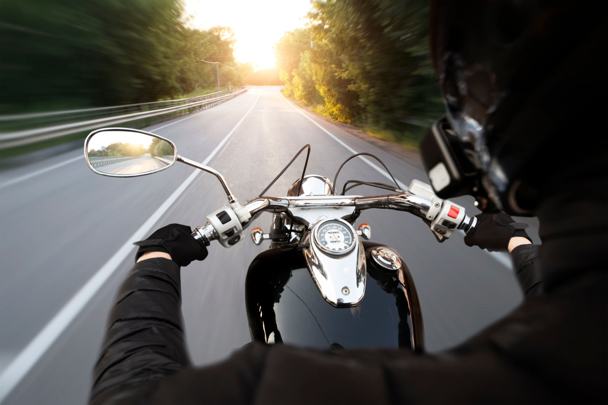 The motorcyclist is riding through the empty asphalt road in the evening The motorcyclist is riding through the empty asphalt road in the evening