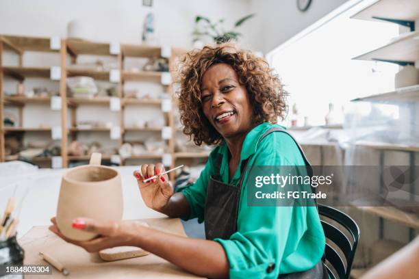 portrait of a senior woman making a craft product on a ceramics workshop - entrepreneur stockfoto's en -beelden