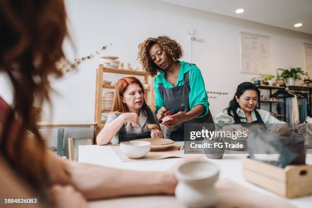 pottery teacher teaching students at a ceramics workshop - black sculptor stock pictures, royalty-free photos & images