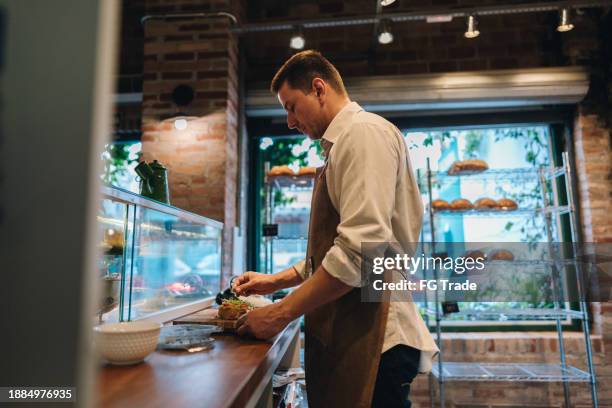 mature man preparing bruschetta at bakery - alfalfa stock pictures, royalty-free photos & images