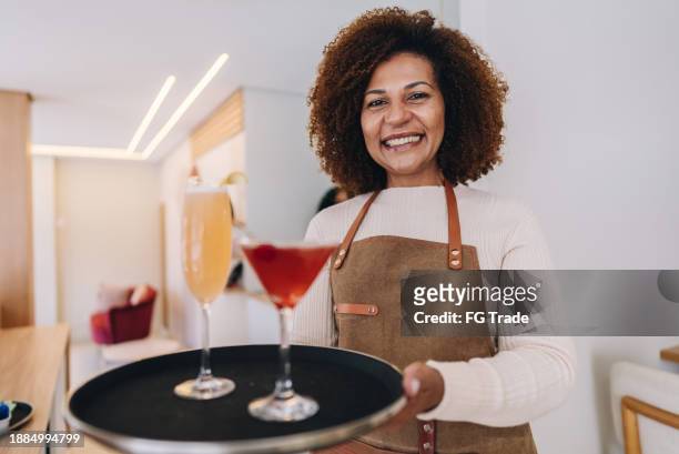 portrait of a mature waitress holding a tray of cocktails at restaurant - cranberry juice stock pictures, royalty-free photos & images