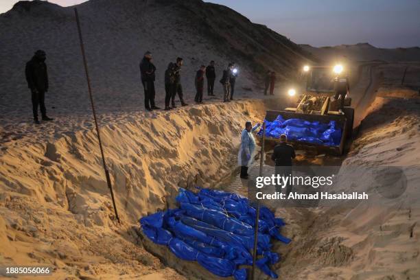 Citizens bury the bodies of Palestinians killed during the war in a mass grave on December 26, 2023 in Rafah, Gaza. Through the Kerem Shalom crossing...