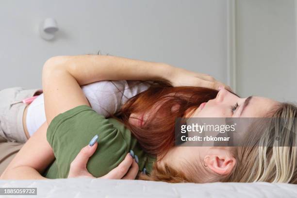 teenager girl comforting friend lying on sofa at home - depression in adolescence - mad girlfriend stock pictures, royalty-free photos & images