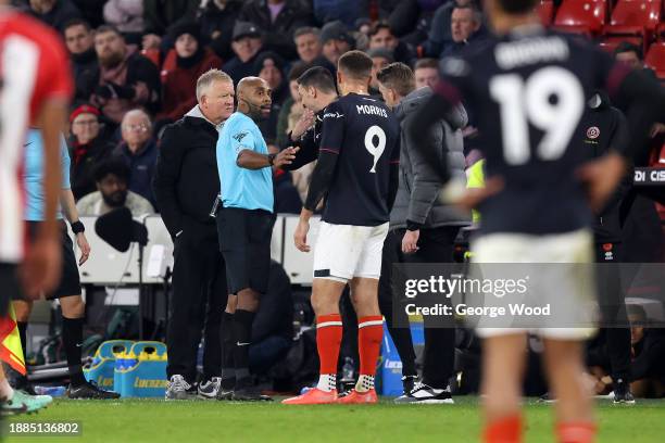 Referee Sam Allison speaks with Chris Wilder, Manager of Sheffield United, and Rob Edwards, Manager of Luton Town, after an off-the-field incident...