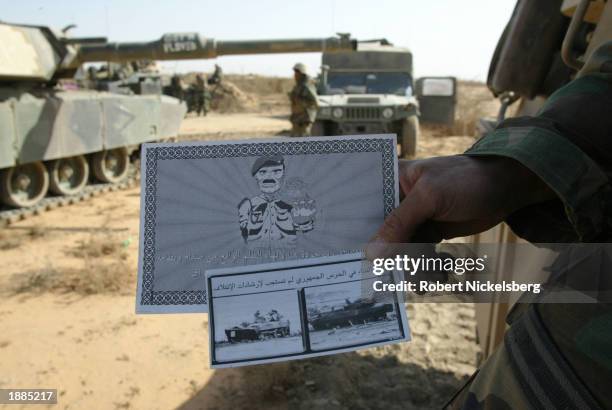 Marine of the 1st Marine Division holds out leaflets air dropped by US forces March 28, 2003 about 93 miles south of Baghdad, Iraq. The bottom...