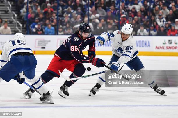 Kirill Marchenko of the Columbus Blue Jackets battles to keep the puck from Calle Jarnkrok and William Nylander of the Toronto Maple Leafs during the...