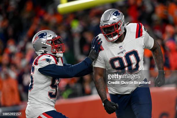 Defensive tackle Christian Barmore of the New England Patriots is congratulated by linebacker Josh Uche after sacking Russell Wilson of the Denver...