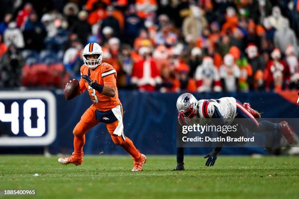 Russell Wilson of the Denver Broncos is pressured by Josh Uche of the New England Patriots in the fourth quarter at Empower Field at Mile High on...