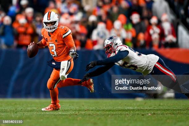 Russell Wilson of the Denver Broncos is pressured by Josh Uche of the New England Patriots in the fourth quarter at Empower Field at Mile High on...