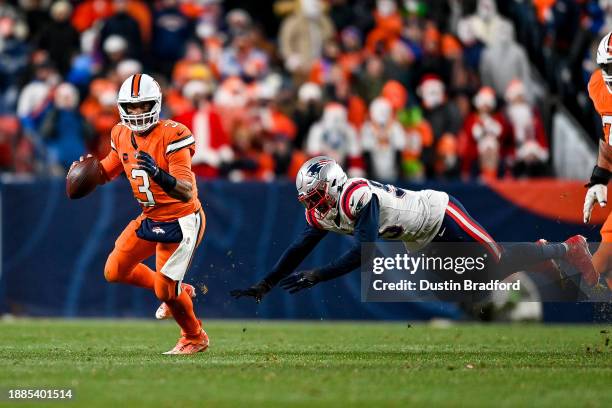 Russell Wilson of the Denver Broncos is pressured by Josh Uche of the New England Patriots in the fourth quarter at Empower Field at Mile High on...