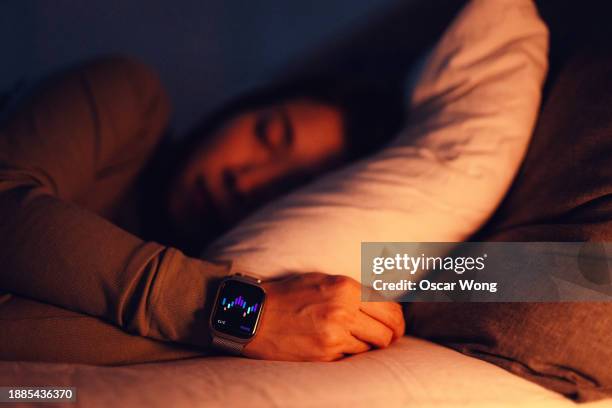 young asian woman using sleep tracker app on smartwatch to monitor her sleep cycle - wearable stock-fotos und bilder