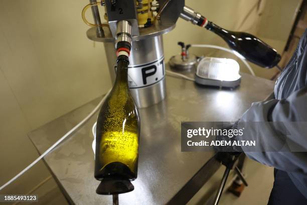 An employee observes the disgorging process aimed at improving the aromatic personality of sparkling wine at Vinkara winery in Kalecik in the...