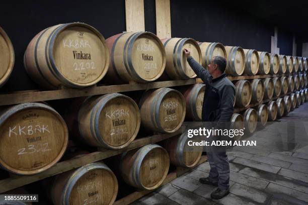 An employee writes numbers on wine barrels at Vinkara winery in Kalecik in the district of Ankara Province on December 18, 2023. Turkish sparkling...