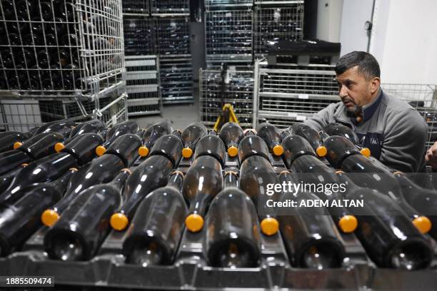 An employee moves bottles of sparkling wine at the Vinkara winery in Kalecik in the district of Ankara Province, on December 18, 2023. Turkish...