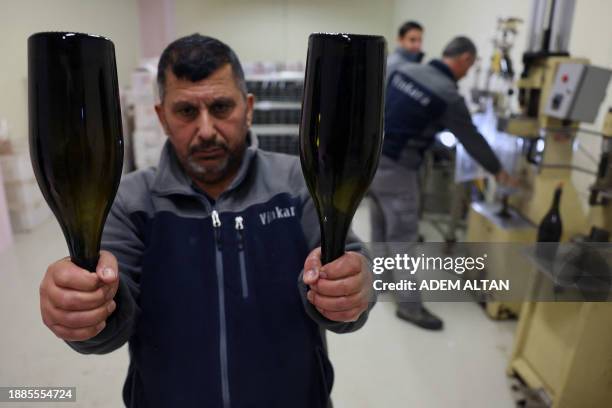 An employee shows sparkling wine bottles after the disgorging process aimed at improving the aromatic personality of sparkling wine at Vinkara winery...