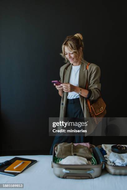 portrait of a beautiful woman using her mobile phone while getting ready to travel - business travel hotel stock pictures, royalty-free photos & images
