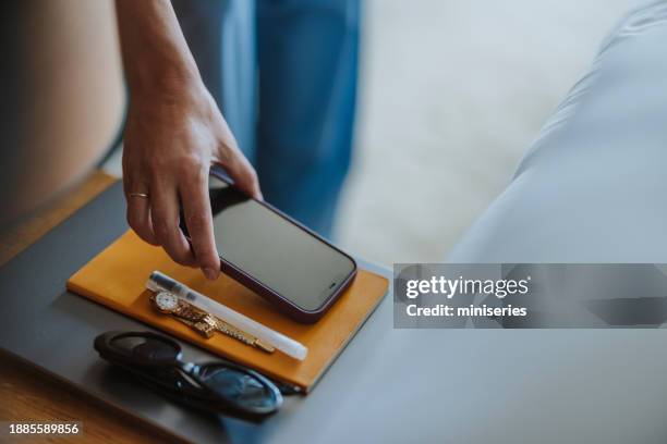 anonymous woman picking up a mobile phone from bedside table (copy space) - bedside table stock pictures, royalty-free photos & images