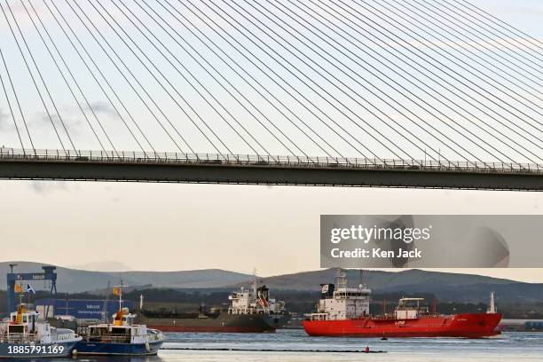 In a busy maritime scene two ships pass each other under the Queensferry Crossing road bridge, as smaller vessels lie alongside a pier at Port Edgar...