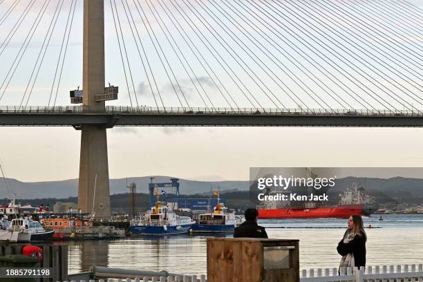 In a busy maritime scene two ships pass each other under the Queensferry Crossing road bridge, as smaller vessels lie alongside a pier at Port Edgar...