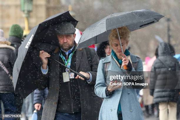 Members of the public shelter from wind and rain under umbrellas on Westminster Bridge in London as Storm Gerrit continues to cause damage to...