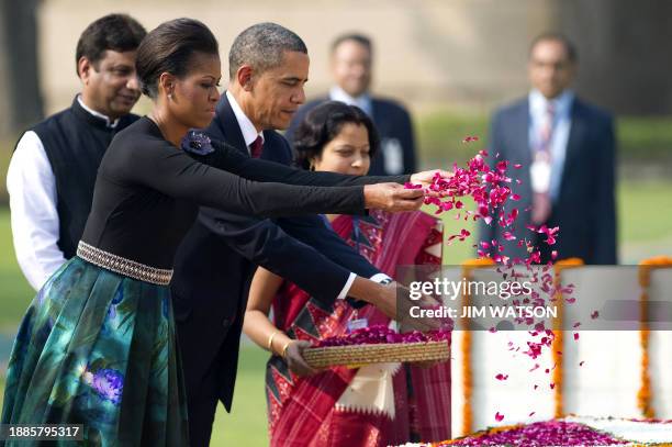 President Barack Obama and First Lady Michelle Obama spread rose petals as they participate in a wreath laying ceremony at Raj Ghat in New Delhi,...