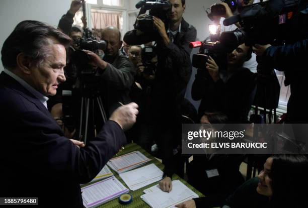 The chairman of the Bosnian tripartite presidency, Haris Silajdzic , talks to members of the electoral board at a polling station in the center of...