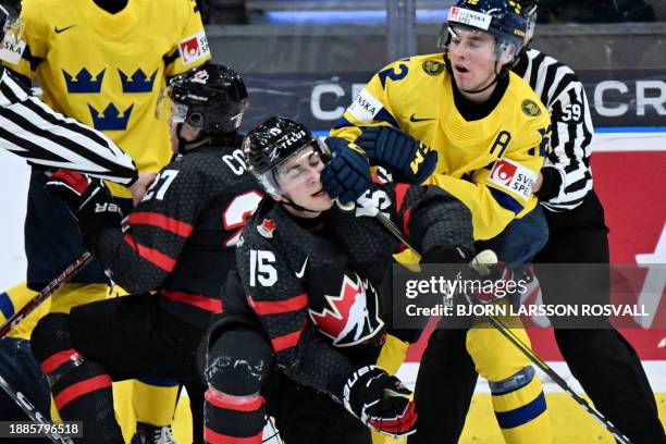 Sweden's Noah Ostlund fights with Canada's Matthew Poitras during the Group A ice hockey match between Canada and Sweden of the IIHF World Junior...