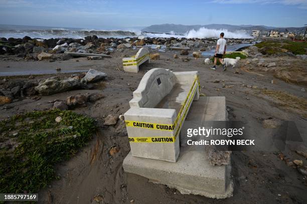 Man walks his dog past concrete benches that were displaced by powerful waves on December 29, 2023 in Ventura, California. Huge surf is battering the...